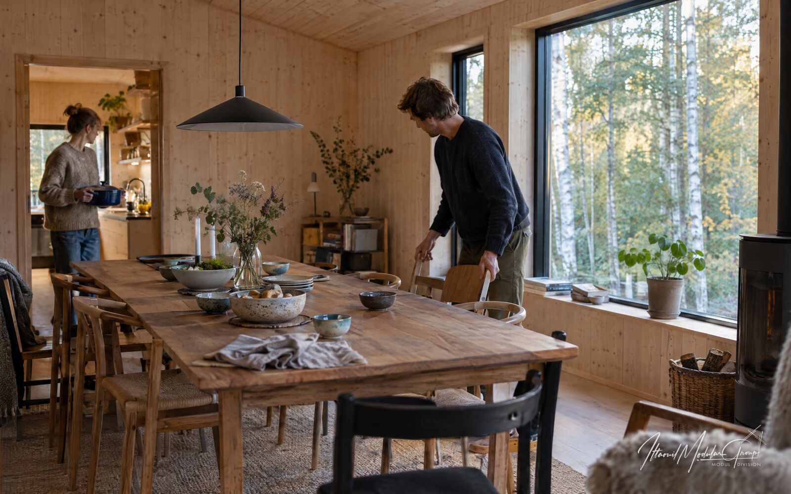 Beboere gør klar til et måltid omkring et træbord i et fælles spiserum